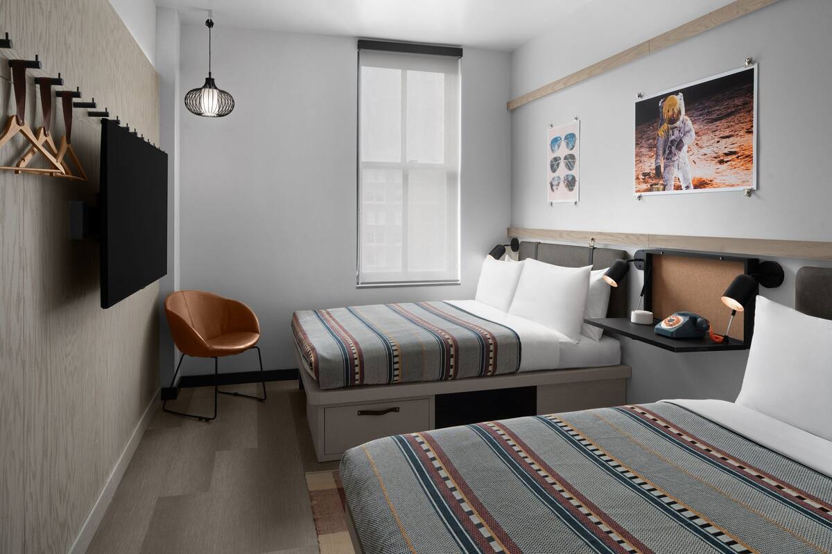 Quarto moderno com cama, cadeira, escrivaninha e janela.