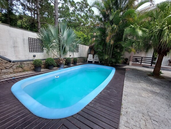A rectangular swimming pool with a blue edge, surrounded by a wooden deck.