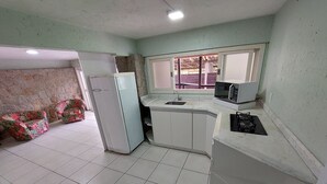 A compact kitchen with white cabinets, a refrigerator, a microwave, and a gas stove. - Loft Barra da Fortaleza - Piscina (Florianópolis)