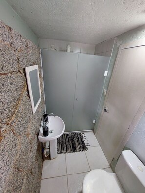 A bathroom with a sink, toilet, and shower area.