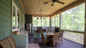 A covered porch with a dining table and chairs, a small kitchen area, and a seating area with a bench. - NEW LISTING ★ WATERFRONT ★ FIREPIT (Vernon)
