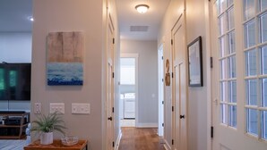 A hallway with wooden flooring, white doors, and a painting on the wall. - NEW LISTING ★ WATERFRONT ★ FIREPIT (Vernon)