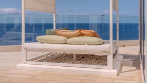 A balcony with a glass enclosure, a white cushioned bed, and a view of the sea. - Villa Blanca Callao Salvaje. First line by the sea (Callao Salvaje)