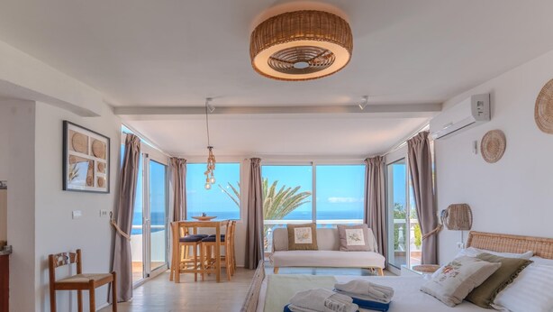 A spacious room with a large bed, a dining area with a table and chairs, and a view of the sea through large windows. - Villa Blanca Callao Salvaje. First line by the sea (Callao Salvaje)