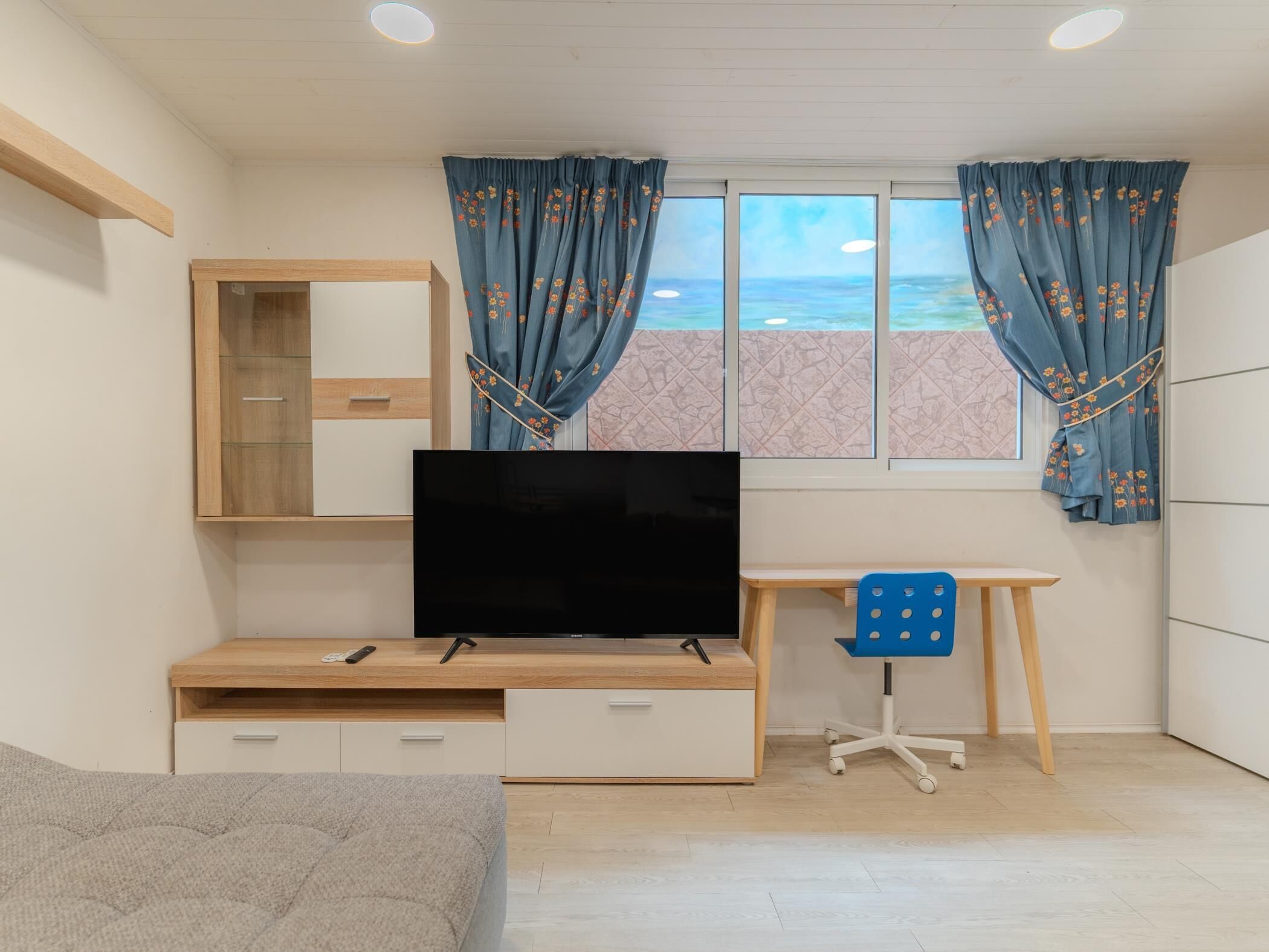 A bedroom with a bed, a TV, a desk, and a chair.