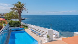 A pool area with a view of the sea, lounge chairs, and a palm tree. - Villa Blanca Callao Salvaje. First line by the sea (Callao Salvaje)