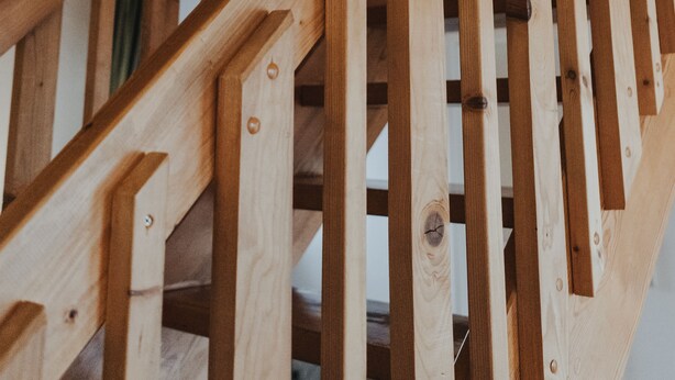 Un escalier en bois au design simple, fabriqué à partir d’un bois de couleur claire, et doté de supports métalliques en haut.