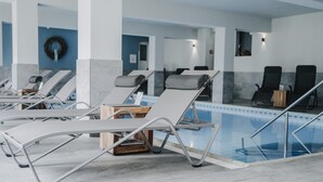 Un espace aménagé au bord de la piscine, avec des chaises longues, une table en bois et une vue dégagée sur la piscine.
