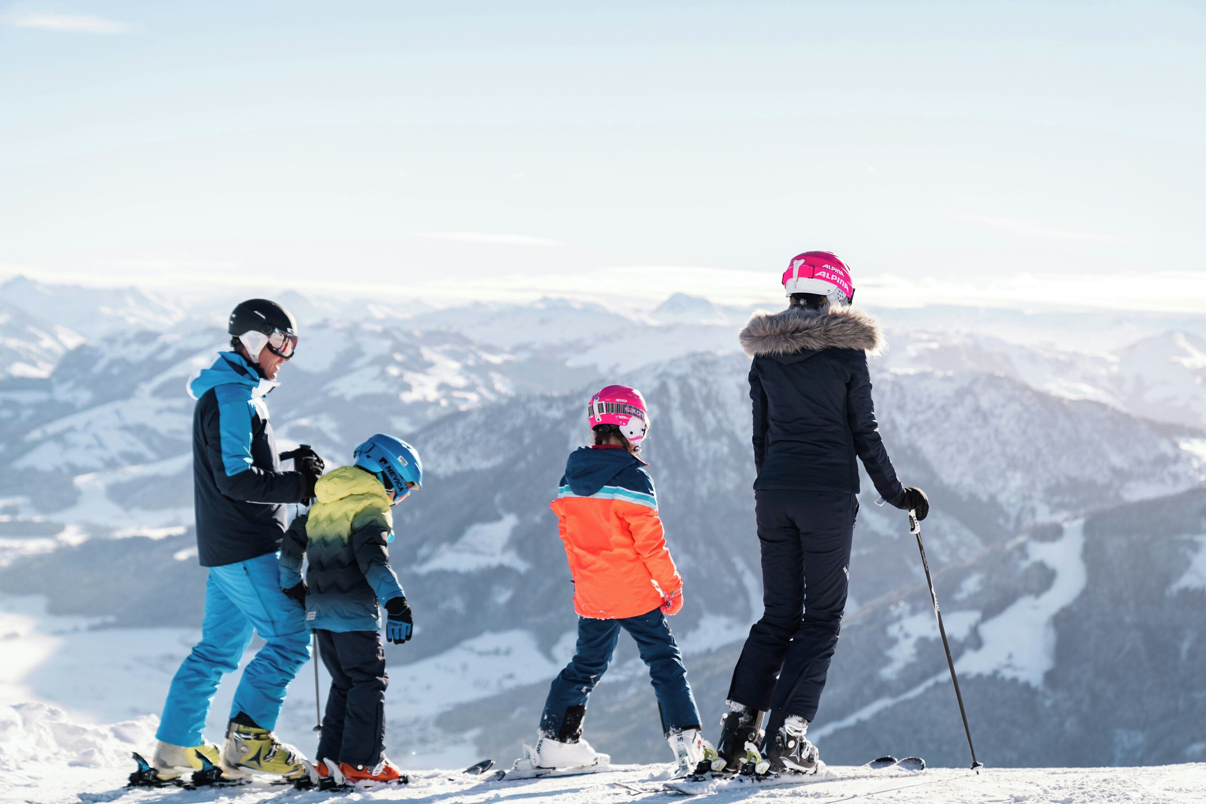 Een groep mensen op een besneeuwde berg met een helder uitzicht over het omliggende landschap.
