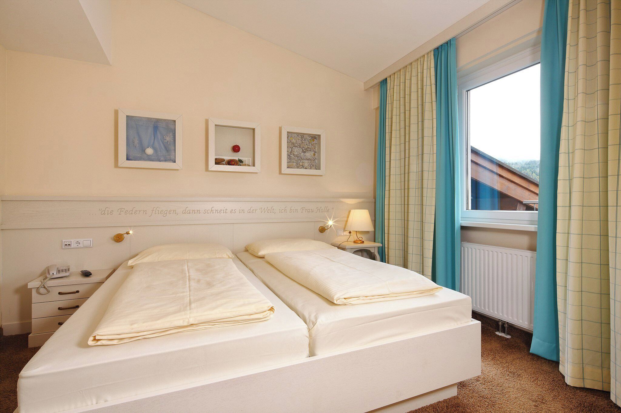 Ein Hotelzimmer mit einem Bett, Nachttischen, einer Lampe und Kunstwerken an der Wand.