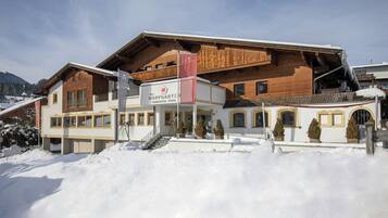 A hotel with a wooden facade, a balcony, and a sign indicating it is a family hotel.