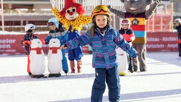 A child ice skating with a mascot and snowmen in the background.