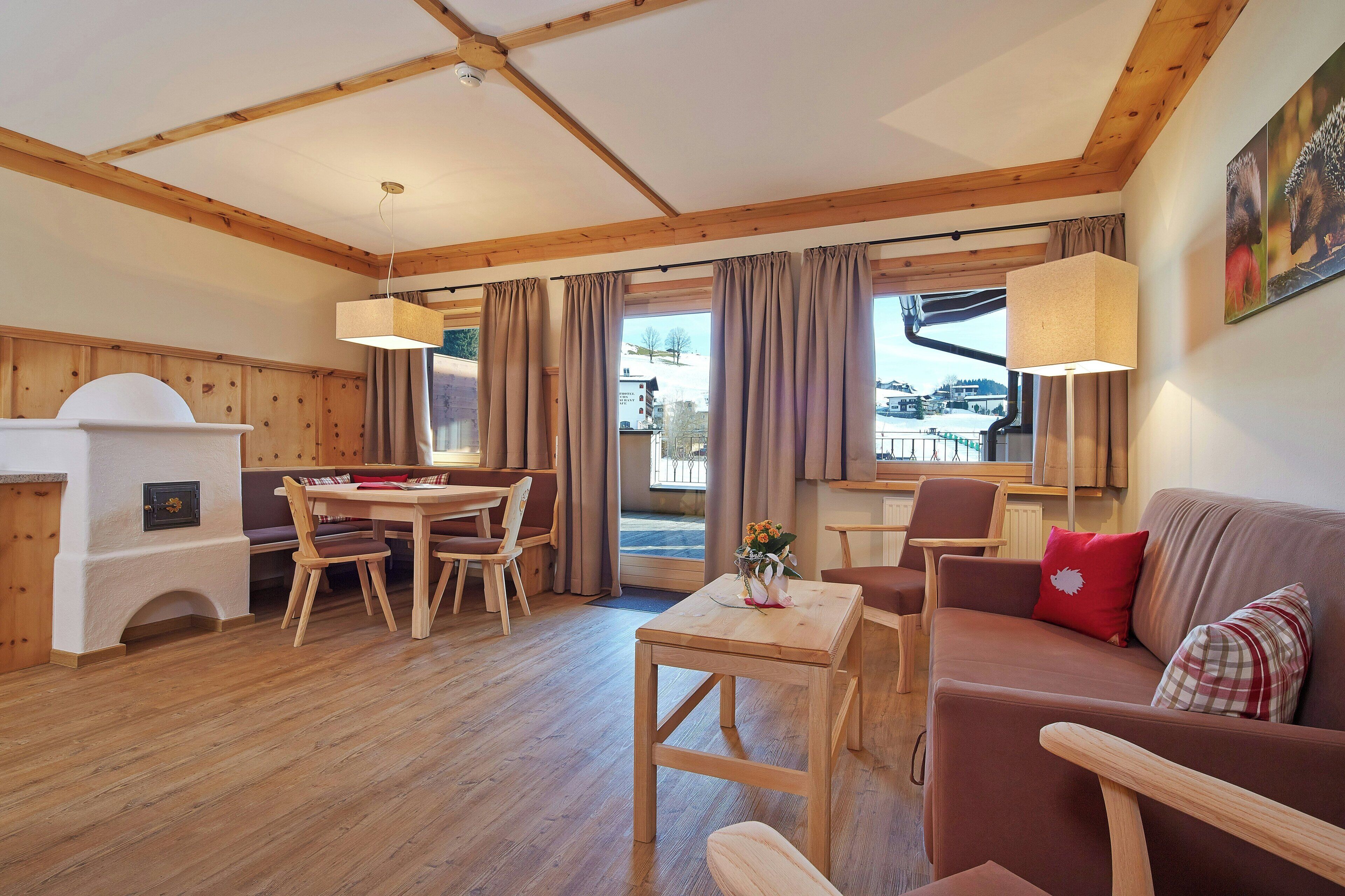 Een gezellige kamer met houten vloeren, een eettafel met stoelen, een bank en een open haard.