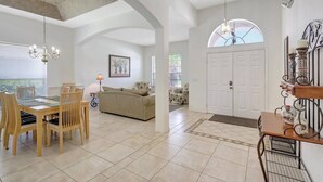 A spacious living area with a dining table, chairs, a sofa, and a chandelier.
