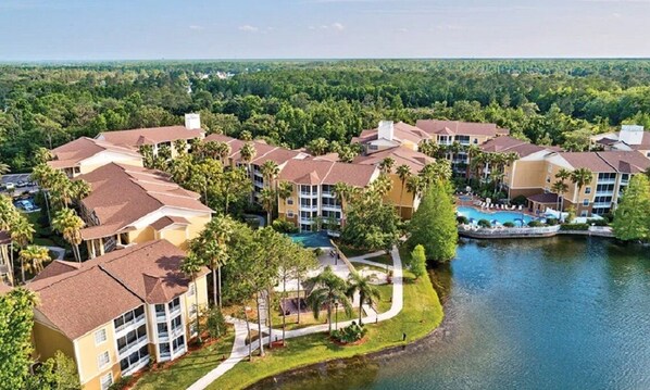 A resort with multiple buildings, a swimming pool, and a lake.