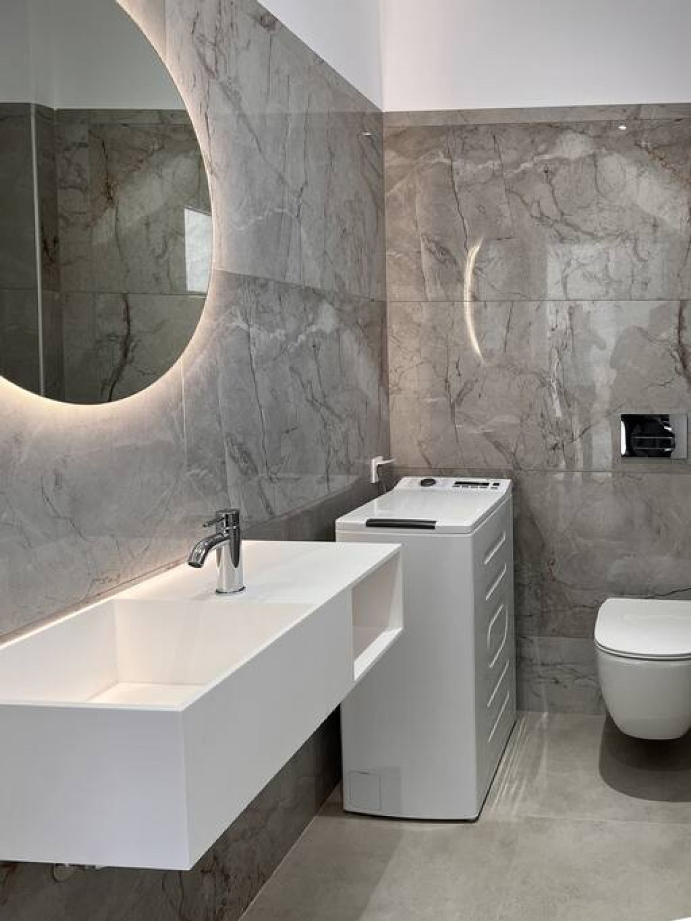 A modern bathroom with a white vanity, a large mirror, and a toilet.