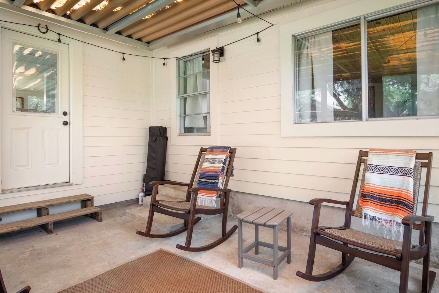 Eine Veranda mit zwei Schaukelstühlen, einem kleinen Tisch und einer Bank.