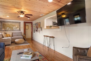 A living room with a sofa, coffee table, and a television mounted on the wall.