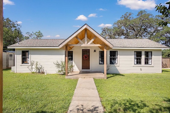 A single-story house with a front porch, a visible number '903' on the door, and a clear sky.