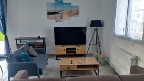 A living room with a sofa, a coffee table, a TV, and a painting on the wall.