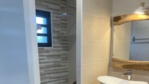 Une salle de bain moderne avec une douche, un lavabo blanc et un meuble-lavabo en bois.