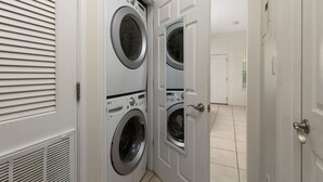 A laundry room with two stacked front-loading washing machines and a door leading to another room.