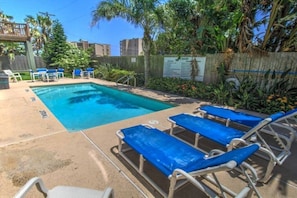 A swimming pool with blue lounge chairs and a wooden deck.