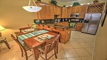 A kitchen with wooden cabinets, a stainless steel refrigerator, and a dining area with a table set for two.