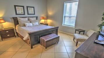 A bedroom with a large bed, bedside tables, a bench, a chair, and a window.
