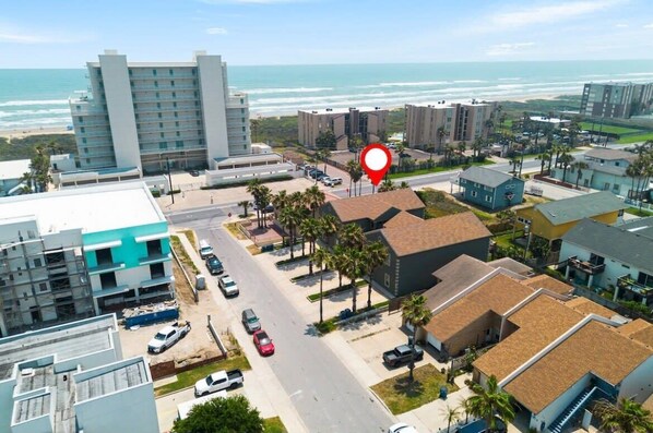 Zona costera urbana con un hotel destacado, un estacionamiento y vistas a la playa.