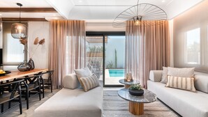 Un salon moderne comprenant un canapé, une table à manger et des chaises, avec vue sur la piscine et un luminaire suspendu.