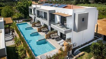 Un edificio moderno con piscina en la azotea, varios balcones y un exuberante jardín.