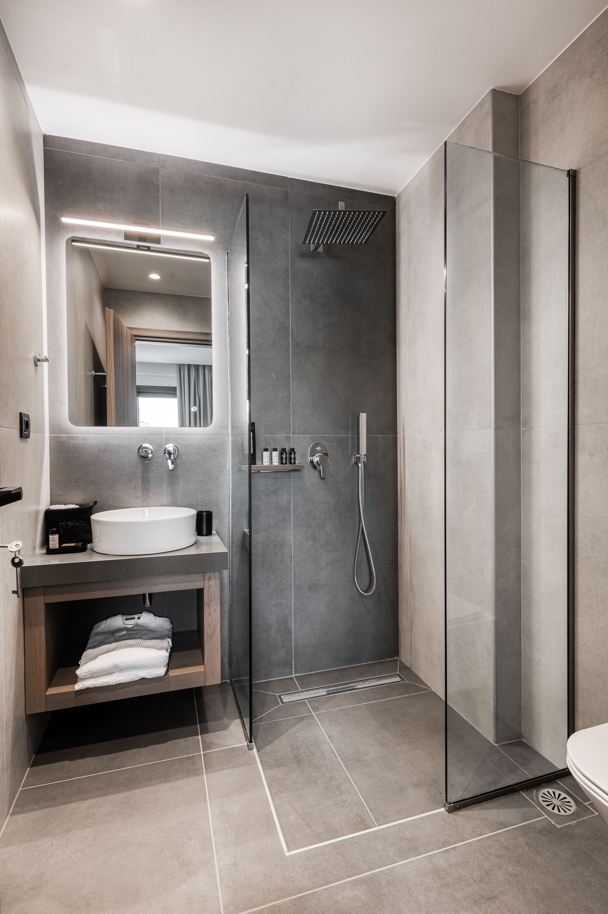 Un baño moderno con cabina de ducha de vidrio, tocador con lavabo y espejo.