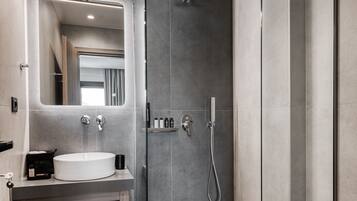 Un baño moderno con cabina de ducha de vidrio, tocador con lavabo y espejo.