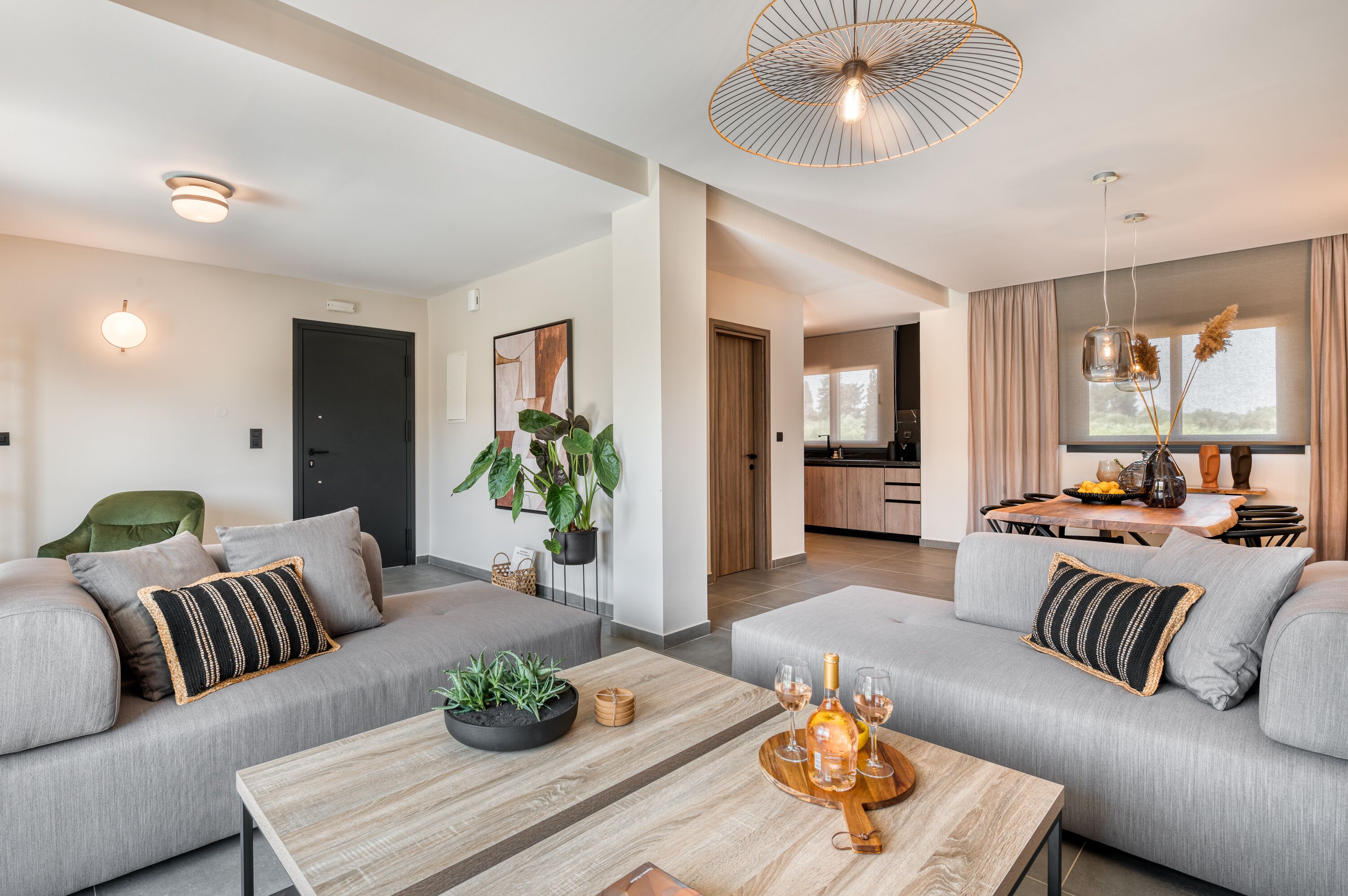 Una sala moderna con un sofá gris, una mesa de centro de madera y una zona de comedor con mesa y sillas.