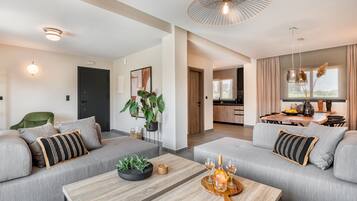 Una sala moderna con un sofá gris, una mesa de centro de madera y una zona de comedor con mesa y sillas.