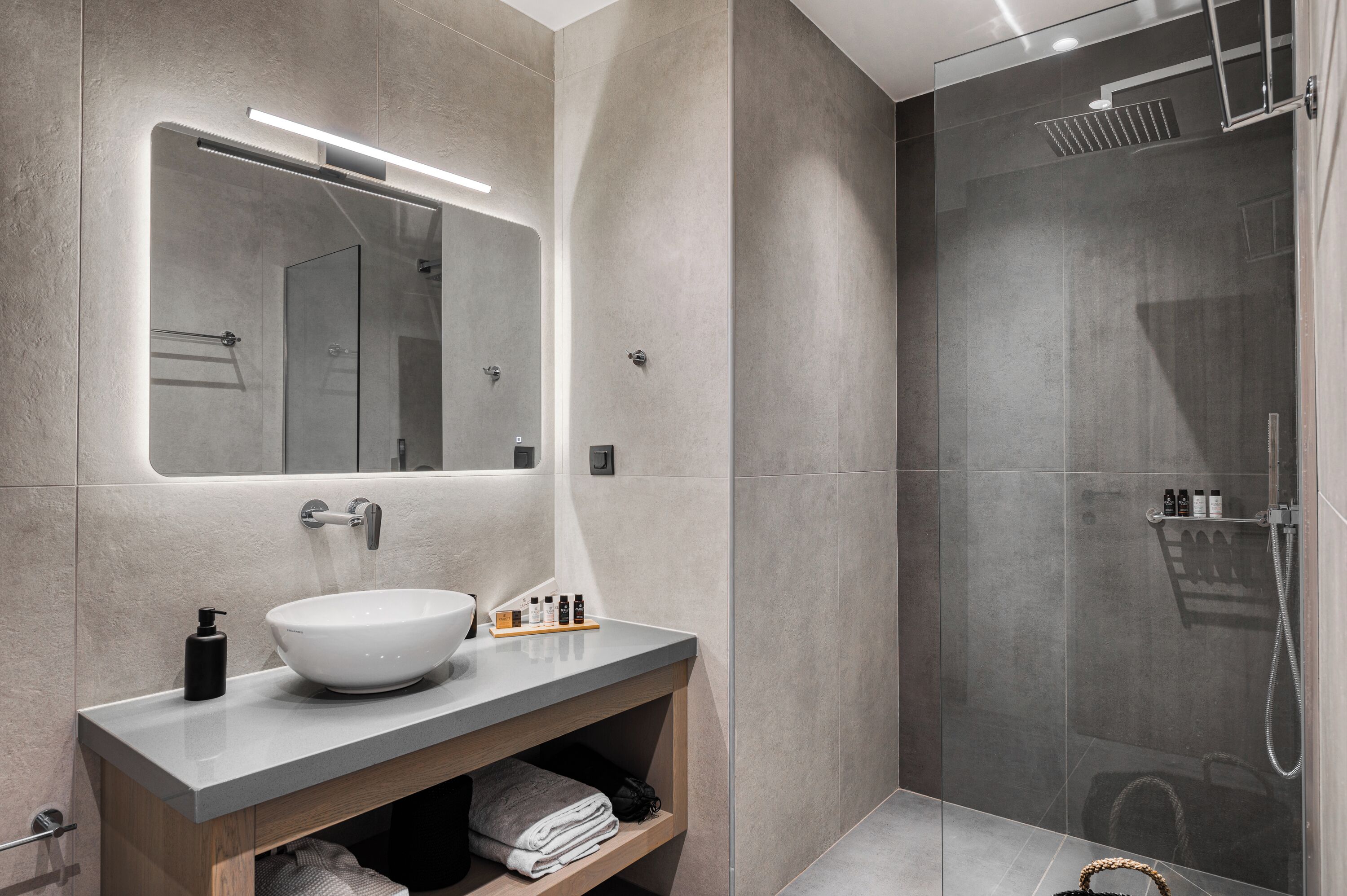 A modern bathroom with a large mirror, a vessel sink, and a walk-in shower.