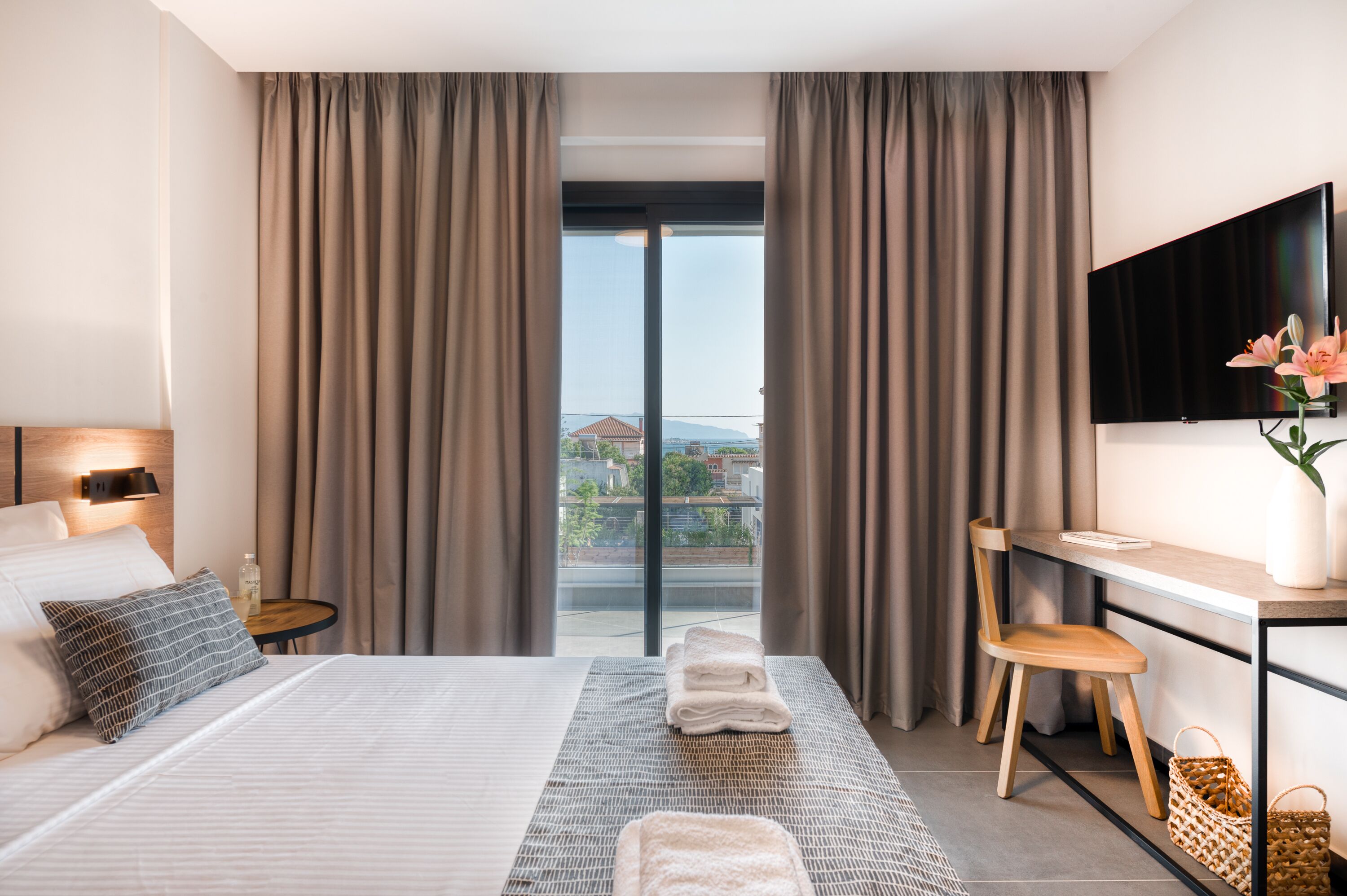 Habitación de hotel con cama, escritorio, silla, televisor y vista a la ciudad.