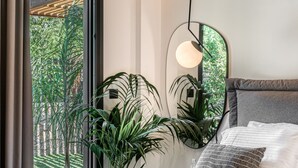 Une chambre moderne avec un lit, un grand miroir et une vue sur la verdure.