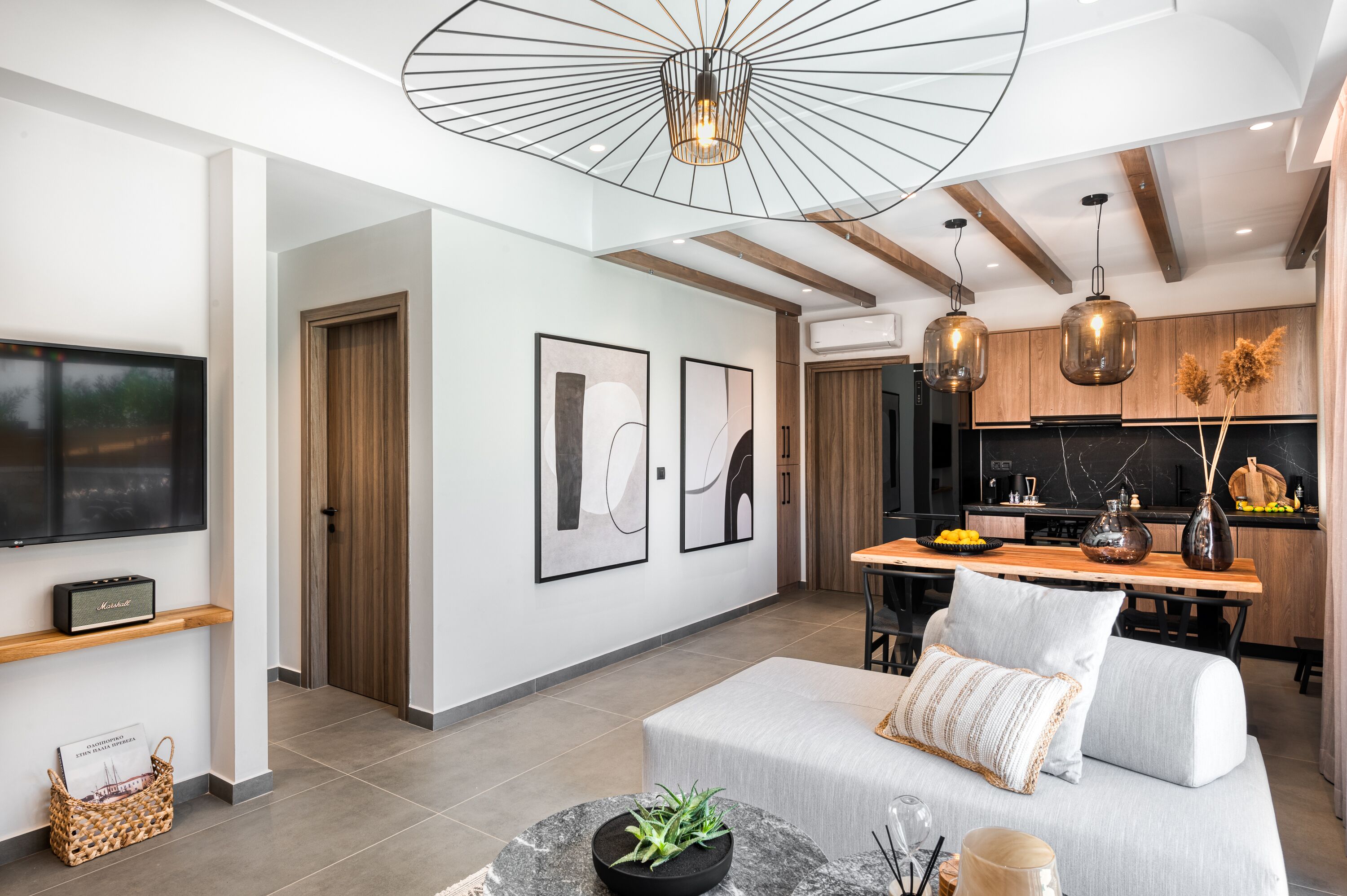Uma sala de estar moderna com uma televisão de tela plana, um sofá e um espaço de jantar com mesa de madeira.
