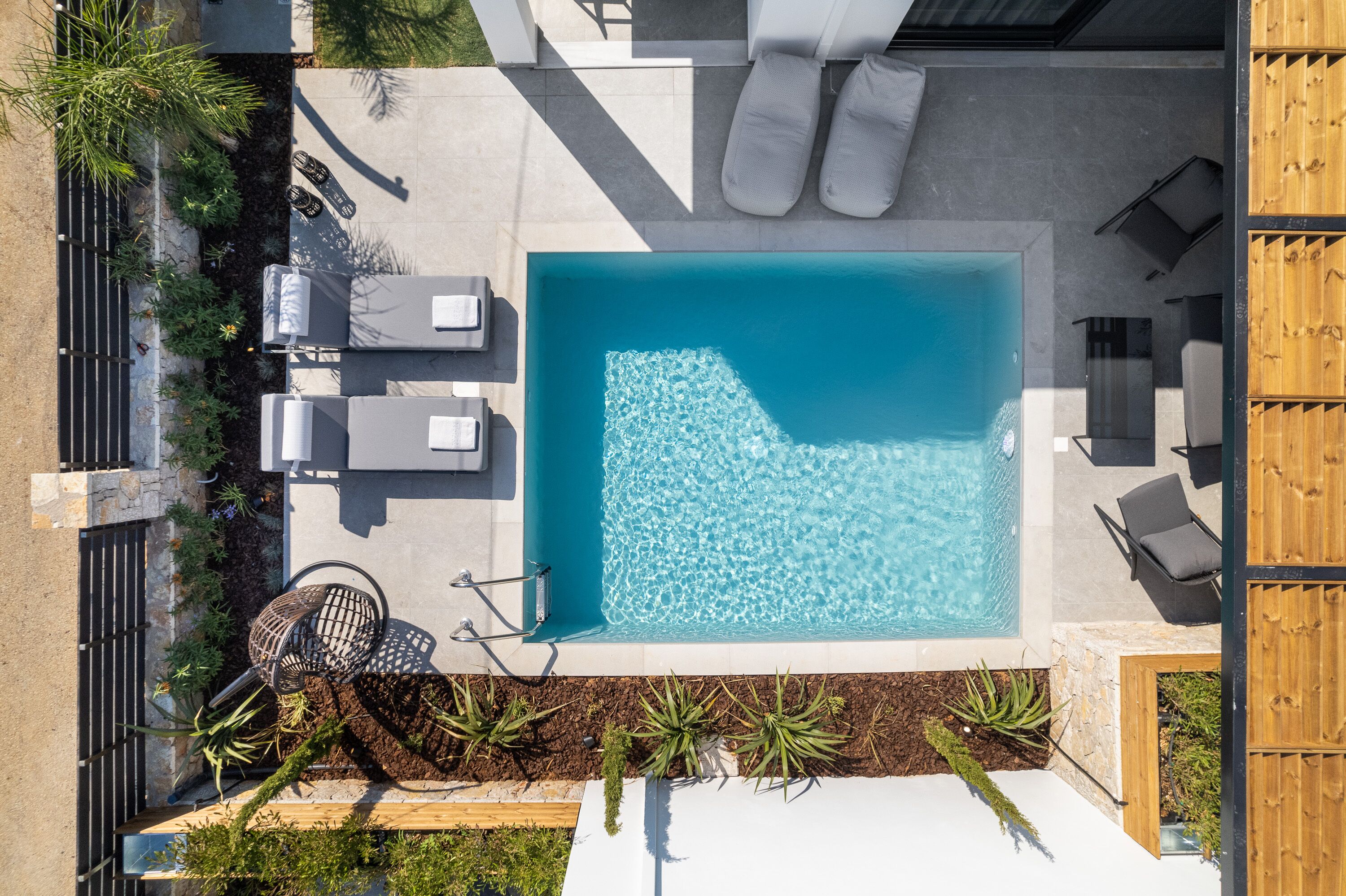 Une piscine sur le toit, de forme géométrique, entourée de chaises longues et d’un petit espace salon.