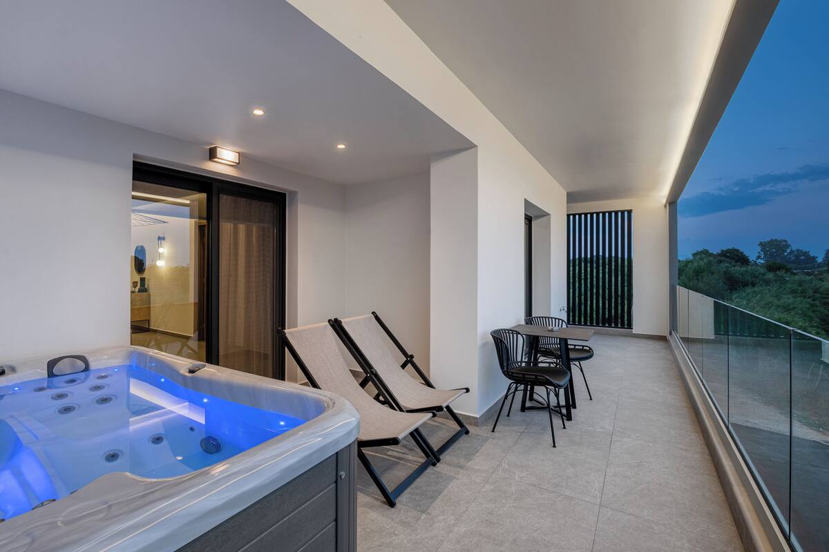Un balcón con un jacuzzi, dos sillas y una mesa.