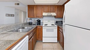 A kitchen with granite countertops, wooden cabinets, a white stove, and a refrigerator. - 2 Bed 2 Bath 1st Fl Condo By Beach w Washer/Dryer (South Padre Island)