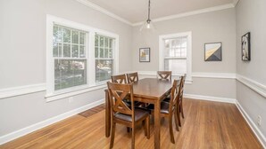 A dining room with a wooden table and chairs, white walls, and large windows with blinds. - 3 Bed 1.5 Bath Home By College Hill & Hospitals (Wichita)
