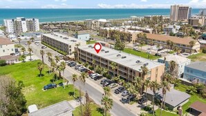An aerial view of a hotel with a parking lot, adjacent buildings, and a view of the ocean. - Lovely 2 Bed 2 Bath 2nd Floor Condo By Beach (South Padre Island)