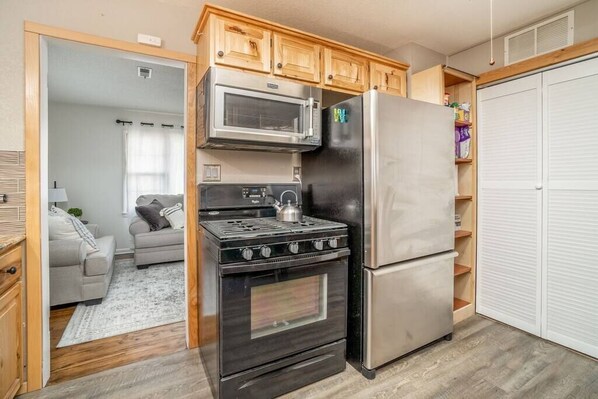 A compact kitchen with a stove, microwave, and refrigerator.