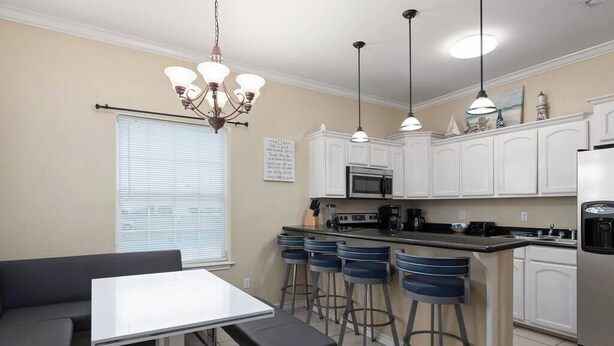 A kitchen with white cabinets, a dining table with benches, and bar stools. - Beautiful 3 Bed 2 Bath 1st Floor Condo Near Beach (South Padre Island)