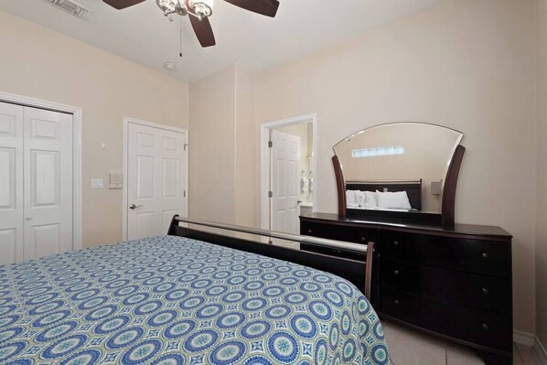 Un dormitorio con cama, cómoda, espejo y ventilador de techo.