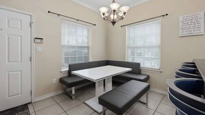A dining area with a white table, black benches, and a chandelier. - Beautiful 3 Bed 2 Bath 1st Floor Condo Near Beach (South Padre Island)
