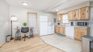 A compact kitchen with wooden cabinets, a white refrigerator, a microwave, and a coffee maker.